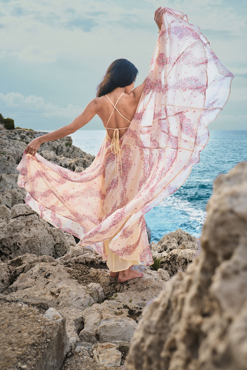 Robe dos nu fluide en mousseline beige et rose à imprimé d’inspiration asiatique par la marque parisienne Phème Paris, photographiée sur la côte du Sud de la France, idéale pour les vacances, les cérémonies d’été et les mariages de destination.