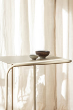 Beistelltisch DENYA mit minimalistischer Tischplatte und dekorativen Schalen im Wohnzimmer.