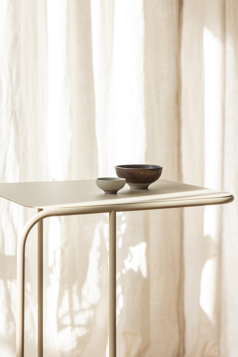 Beistelltisch DENYA mit minimalistischer Tischplatte und dekorativen Schalen im Wohnzimmer.