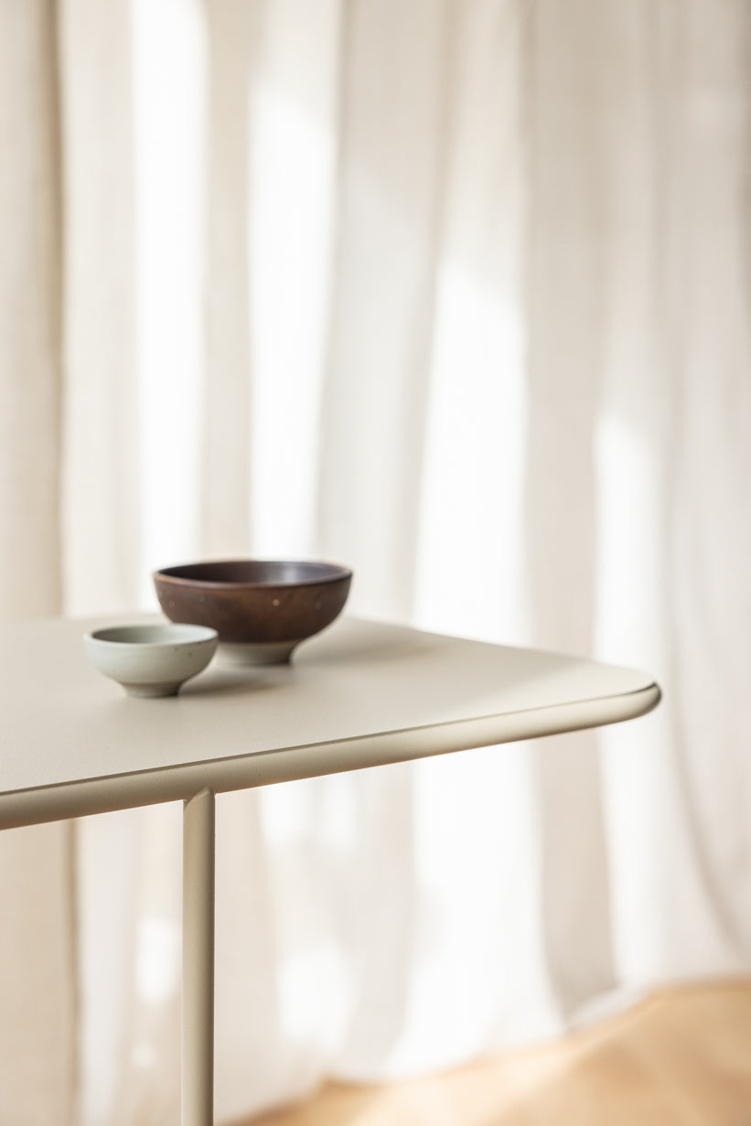 Beistelltisch DENYA mit minimalistischer Tischplatte und dekorativen Schalen aus Keramik und Holz.