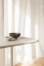 Beistelltisch DENYA mit minimalistischer Tischplatte und dekorativen Schalen aus Keramik und Holz.
