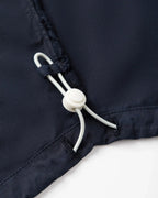 Détail d’un jean en popeline navy, tissu léger 100% coton, avec un cordon de serrage ajustable pour un maintien personnalisé et un confort optimal.