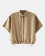 Chemise femme beige en tissu fluide avec coupe ample, col classique et bas resserré par un cordon ajustable.