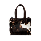 Dark brown and cream cow print pattern tote bag with dark brown rope handles on a white background. When the inner straps are joined, the bag takes on a more rounded shape.