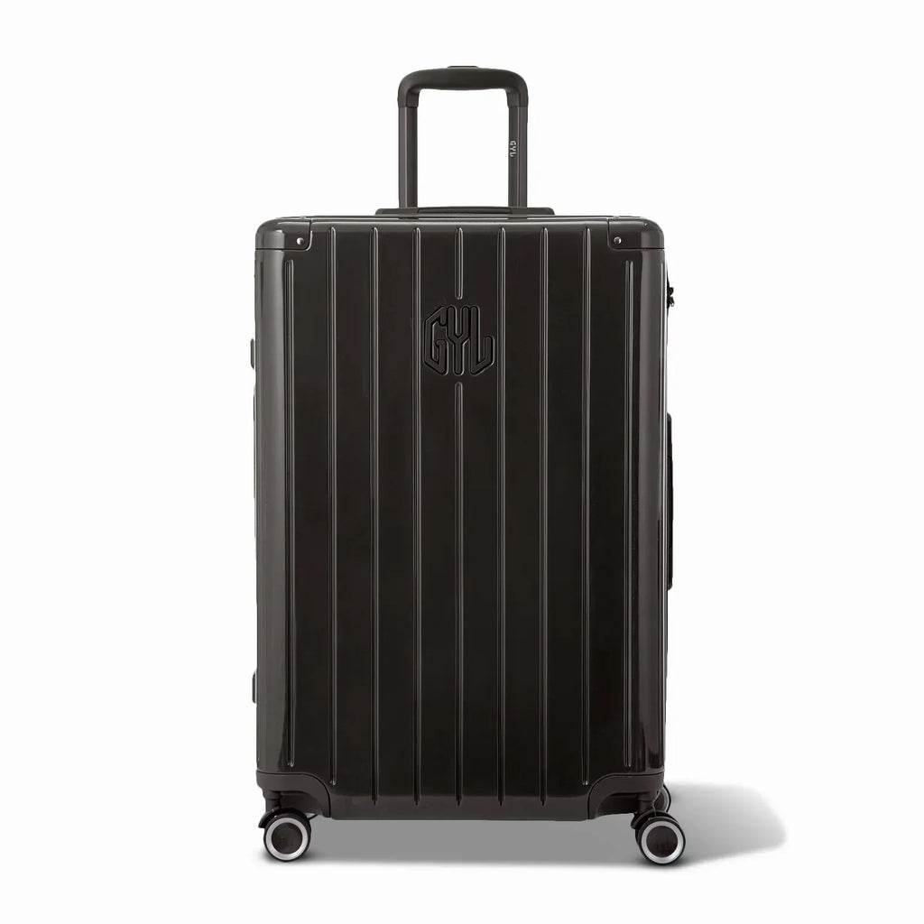 Vue avant de la valise rigide GYL Intemporelle noir, logo embossé et roulettes 360 degrés. #couleur_noir