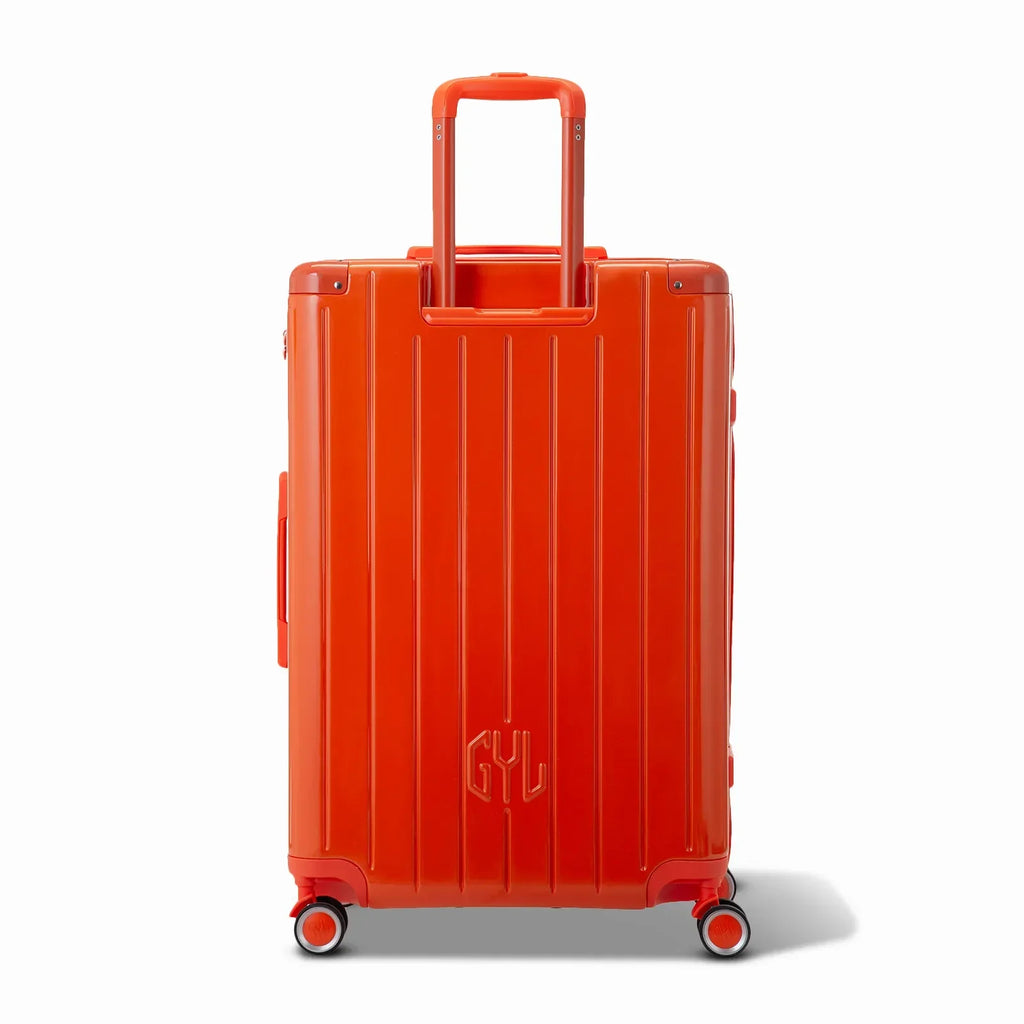 Vue arrière de la valise rigide GYL Intemporelle orange avec poignées intégrées et roulettes pivotantes. #couleur_orange foncé
