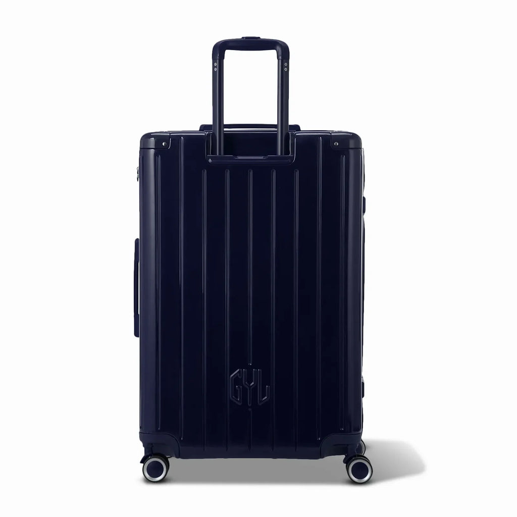 Vue arrière de la valise rigide GYL Intemporelle marine avec poignées intégrées et roulettes pivotantes. #couleur_marine