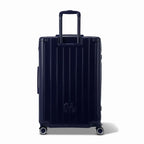 Vue arrière de la valise rigide GYL Intemporelle marine avec poignées intégrées et roulettes pivotantes. #couleur_marine