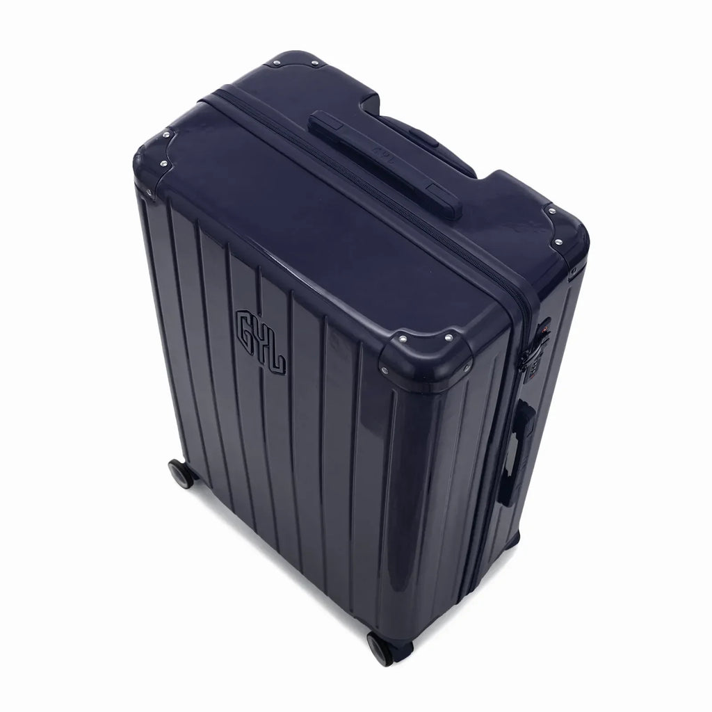 Vue en angle de la valise rigide GYL Intemporelle marine avec coins renforcés et coque nervurée brillante. #couleur_marine