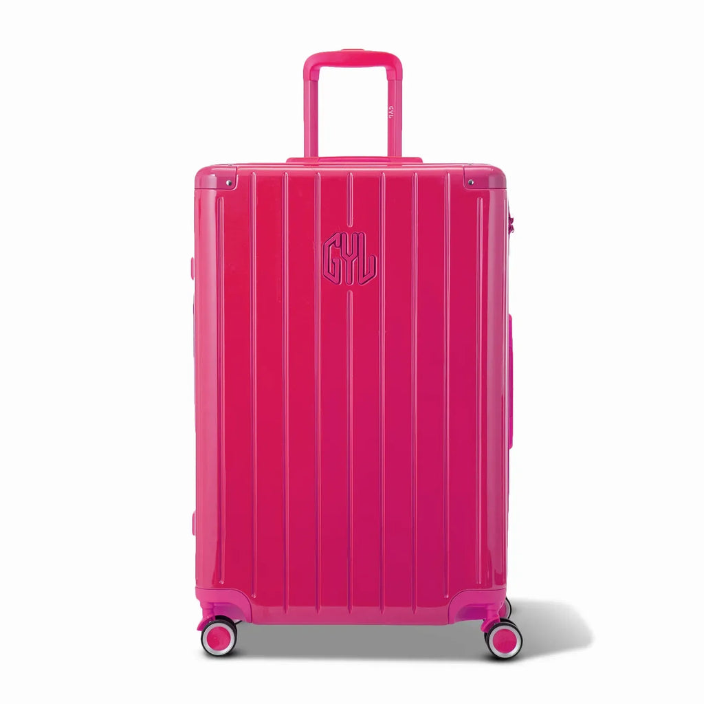 Vue avant de la valise rigide GYL Intemporelle fuchsia, logo embossé et roulettes 360 degrés. #couleur_fuchsia