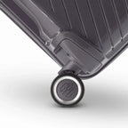 Détail de la roue avec logo GYL sur la valise Signature argent en polypropylène brillant. #couleur_argent