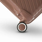 Détail de la roue avec logo GYL sur la valise Signature champagne en polypropylène brillant. #couleur_champagne