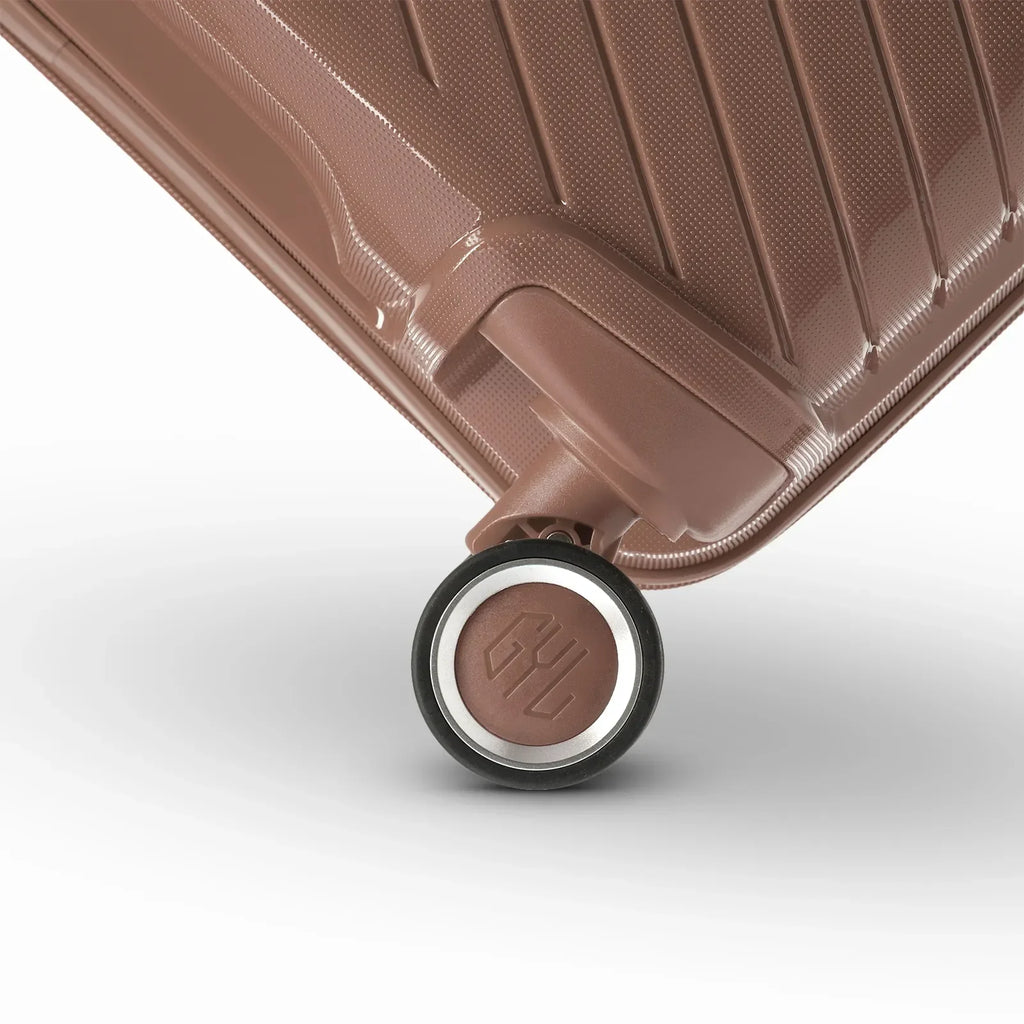 Détail de la roue avec logo GYL sur la valise Signature champagne en polypropylène brillant. #couleur_champagne