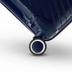 Détail de la roue avec logo GYL sur la valise Signature marine en polypropylène brillant. #couleur_marine