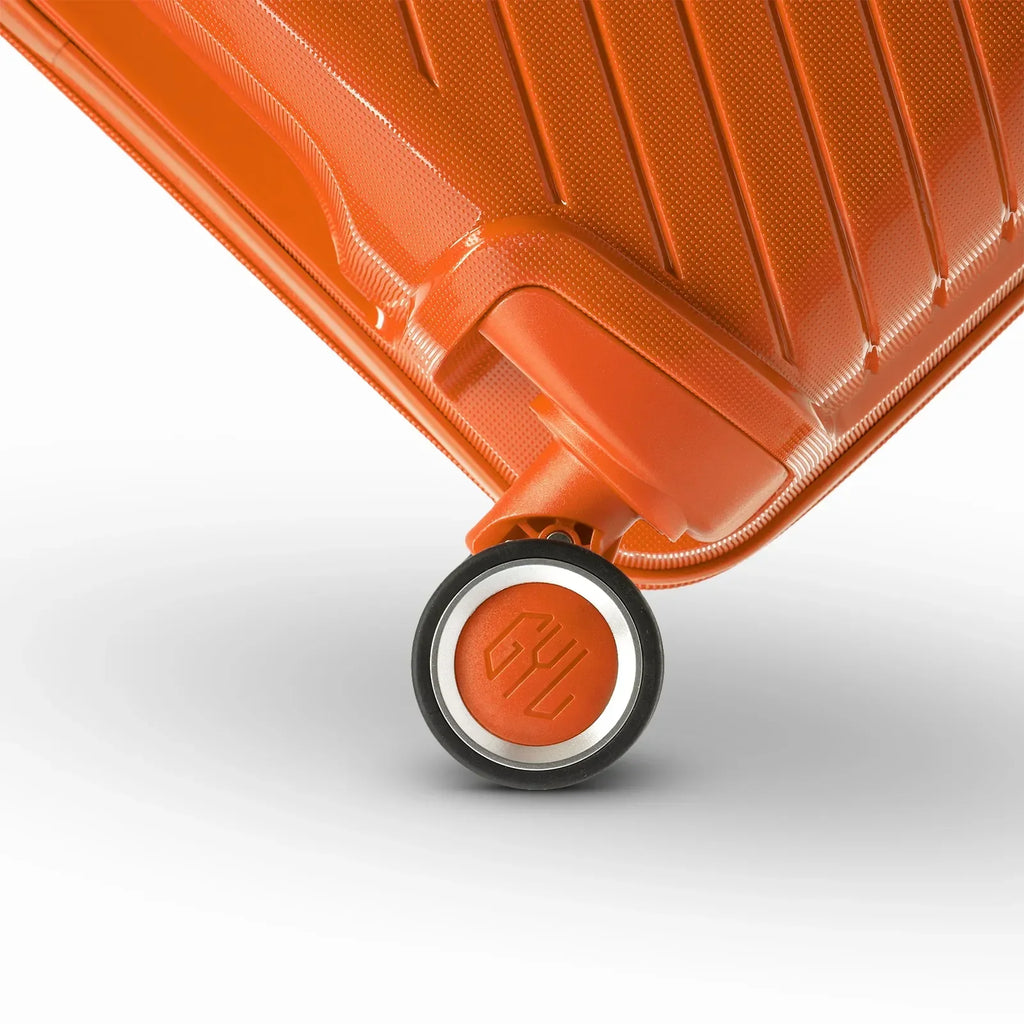 Détail de la roue avec logo GYL sur la valise Signature orange en polypropylène brillant. #couleur_orange