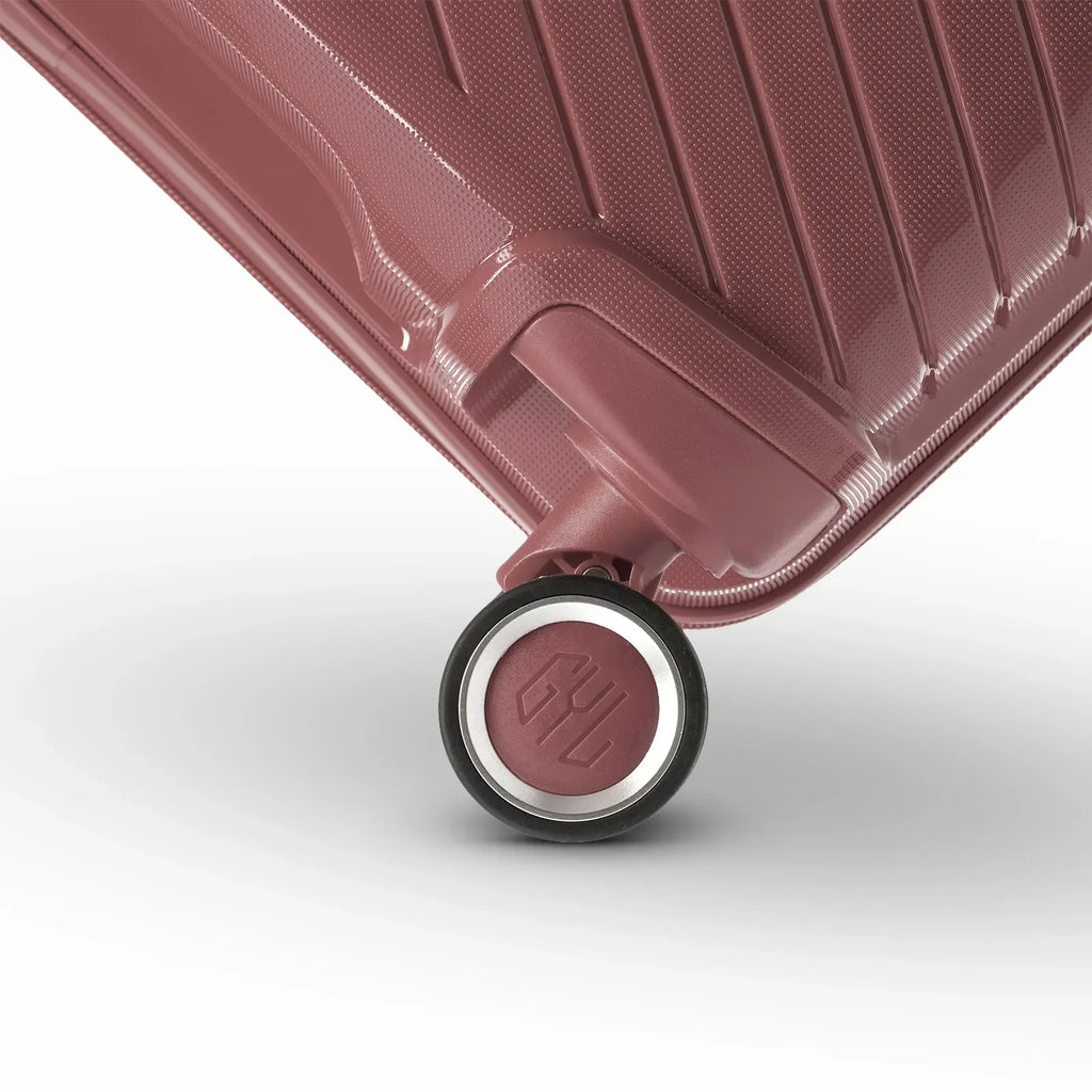 Détail de la roue avec logo GYL sur la valise Signature rose gold en polypropylène brillant. #couleur_rose gold