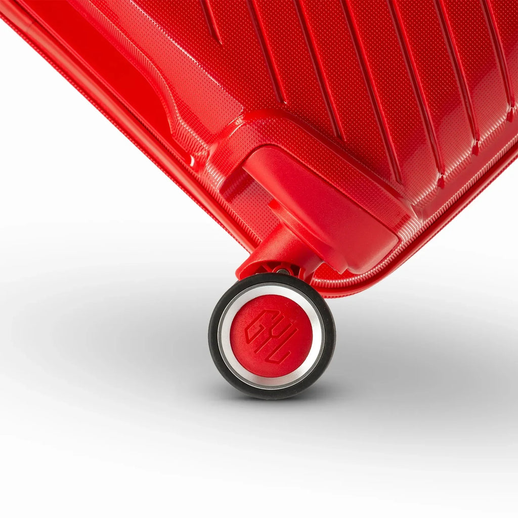 Détail de la roue avec logo GYL sur la valise Signature rouge en polypropylène brillant. #couleur_rouge