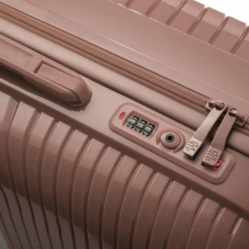 Détail de la serrure TSA intégrée et des curseurs sur la valise Signature champagne. #couleur_champagne