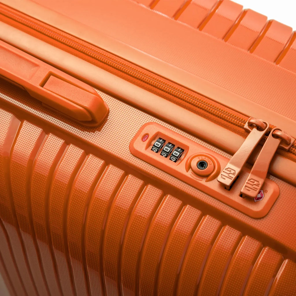 Détail de la serrure TSA intégrée et des curseurs sur la valise Signature orange. #couleur_orange