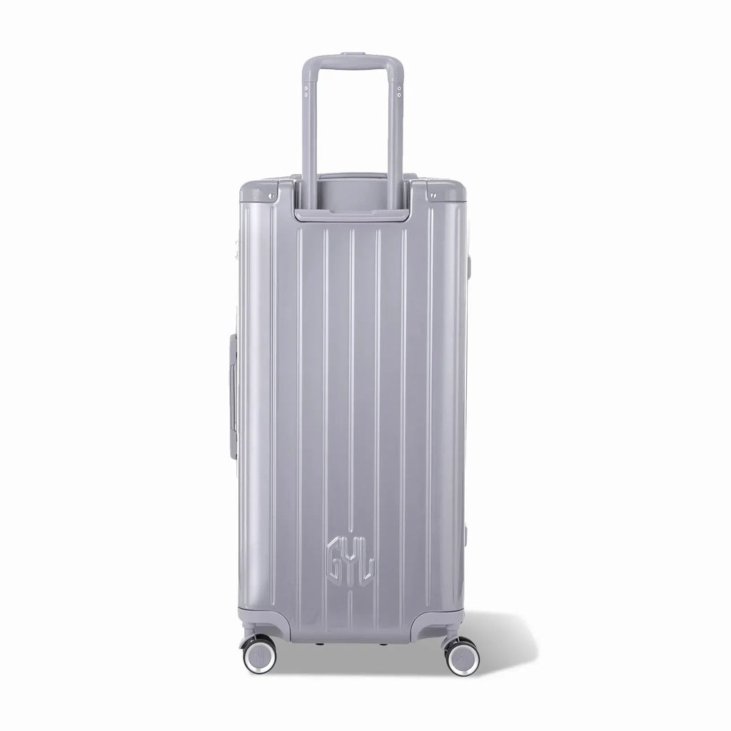 Dos de la valise trunk GYL XL argent avec trolley télescopique sorti et logo embossé. #couleur_argent
