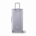 Dos de la valise trunk GYL XL argent avec trolley télescopique sorti et logo embossé. #couleur_argent