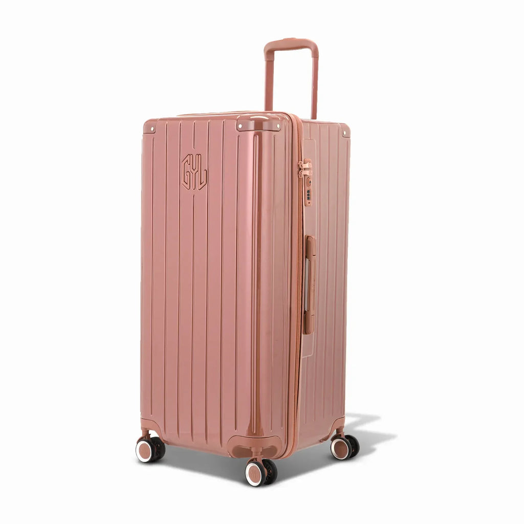 Valise trunk GYL taille XL en polycarbonate rose gold vue de trois quarts, avec trolley déployé et roues 360°. #couleur_rose gold