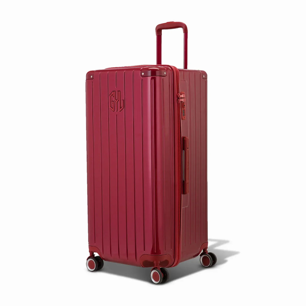 Valise trunk GYL taille XL en polycarbonate rouge foncé vue de trois quarts, avec trolley déployé et roues 360°. #couleur_rouge foncé