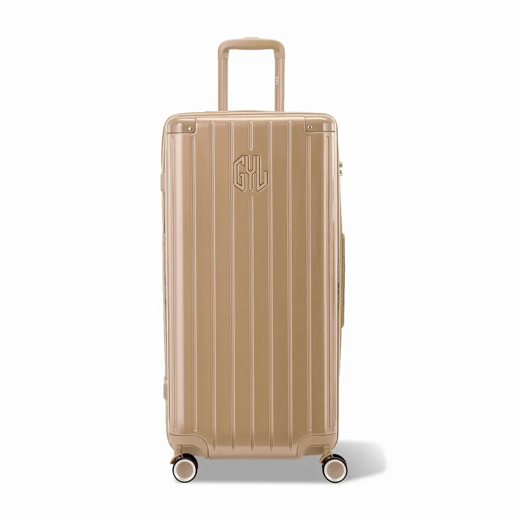 Valise trunk GYL taille XL en polycarbonate champagne vue de face, avec trolley déployé et roues 360°.  #couleur_champagne