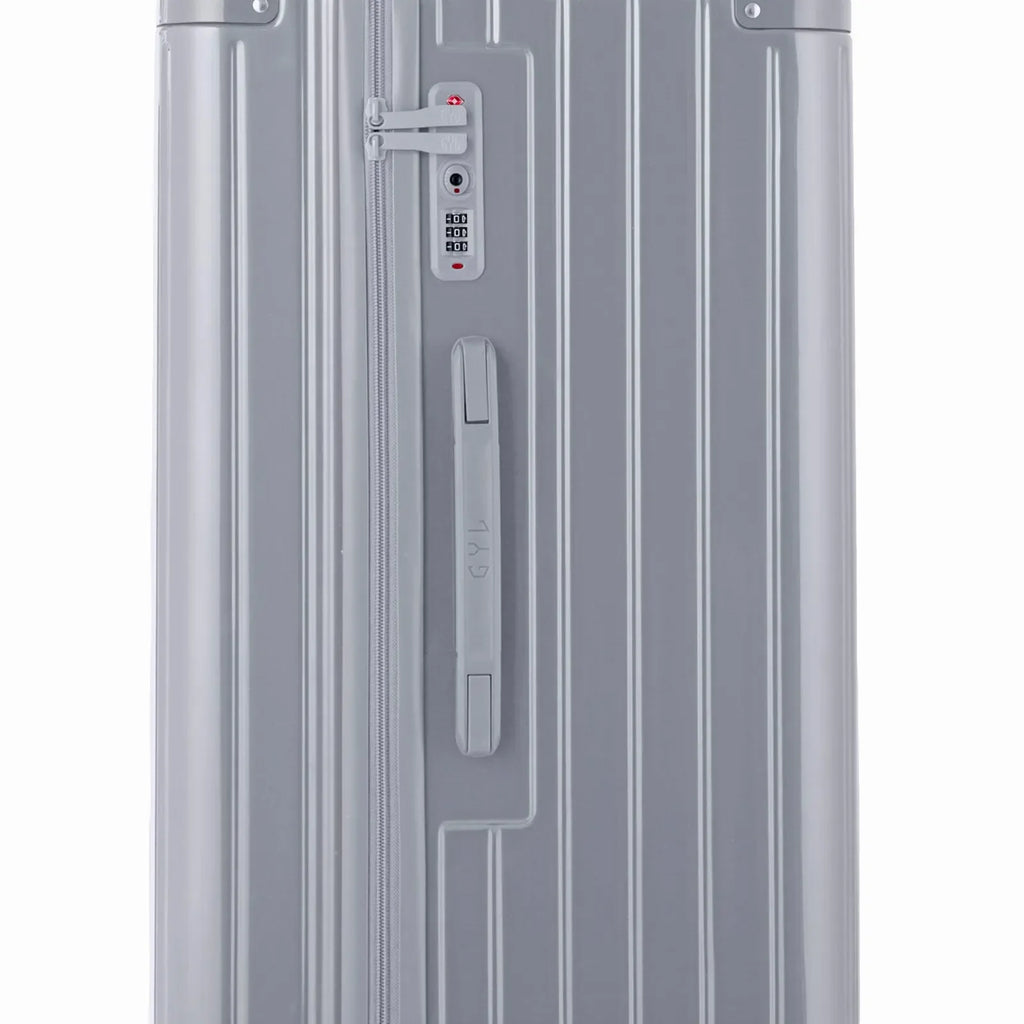 Détail de la serrure TSA et de la poignée latérale sur la valise trunk argent. #couleur_argent