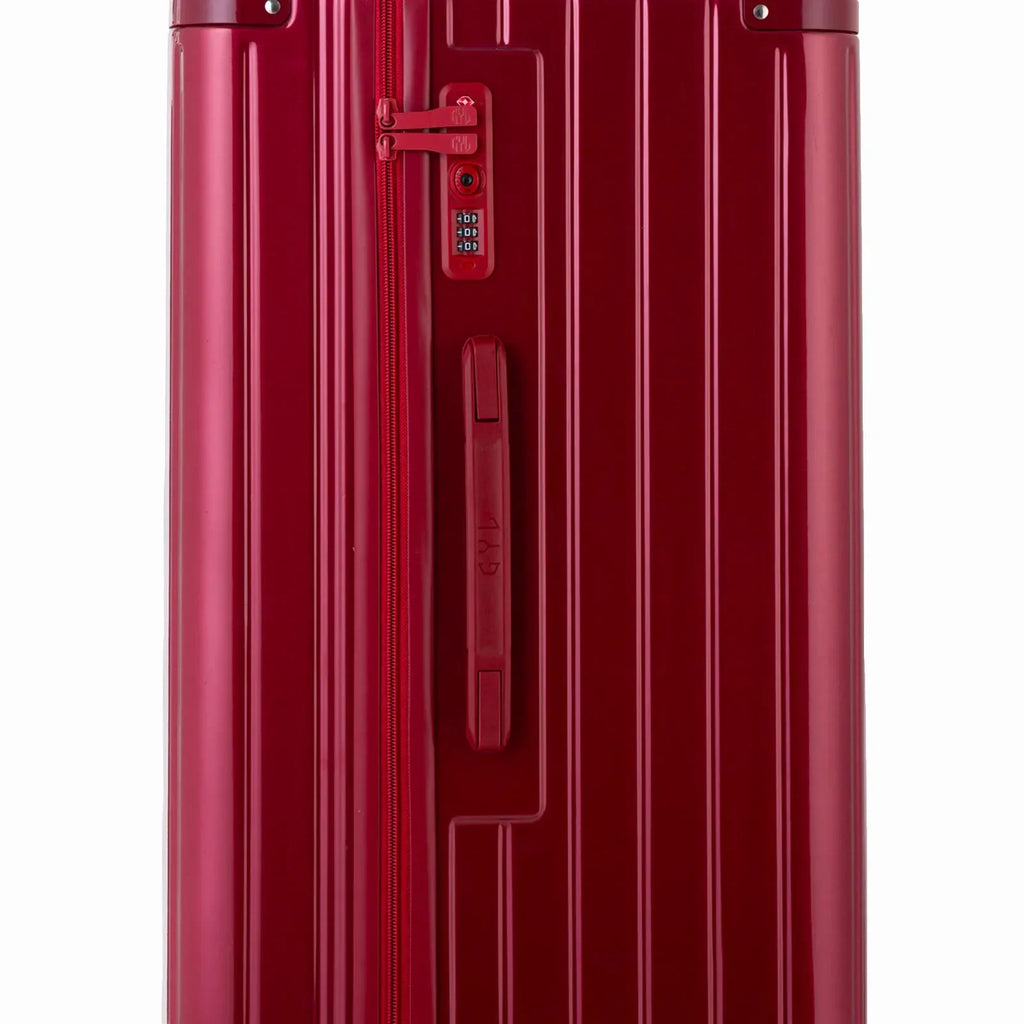 Détail de la serrure TSA et de la poignée latérale sur la valise trunk rouge foncé. #couleur_rouge foncé