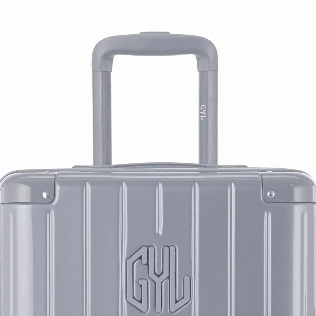 Zoom sur la poignée trolley et le logo GYL de la valise trunk argent. #couleur_argent
