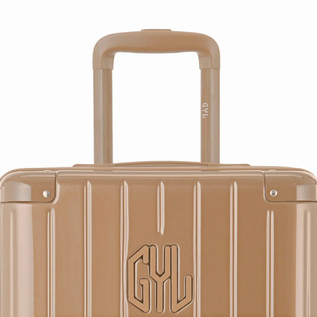 Zoom sur la poignée trolley et le logo GYL de la valise trunk champagne. #couleur_champagne