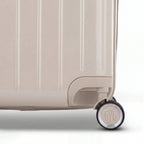 Détail de la roue et du logo GYL sur le bas de la valise trunk nude en polycarbonate brillant. #couleur_nude