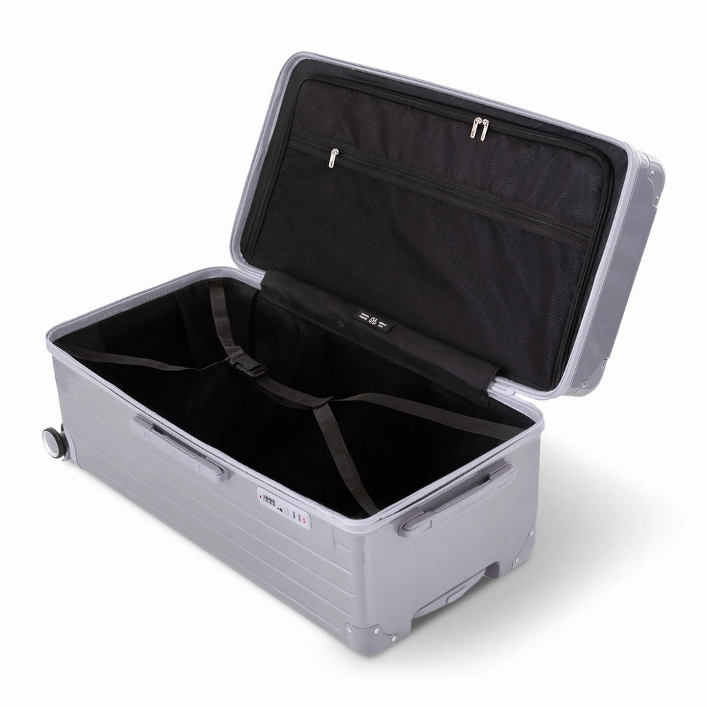 Intérieur de la valise trunk GYL XL argent ouvert, avec sangles croisées. #couleur_argent