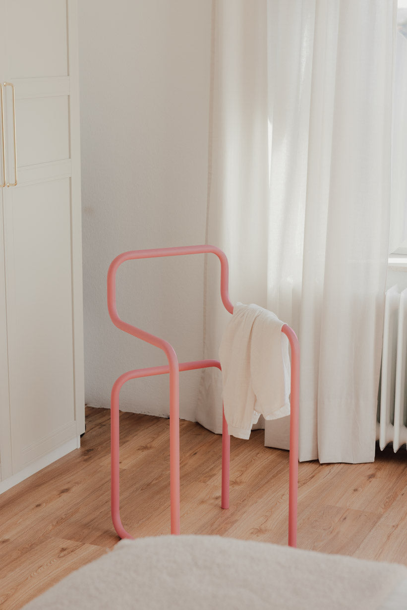 Minimalist Herrendiener in Rosa mit einem Kleidungsstück auf der Rückenlehne, ideal für Schlafzimmer.