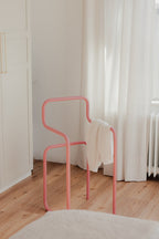 Minimalist Herrendiener in Rosa mit einem Kleidungsstück auf der Rückenlehne, ideal für Schlafzimmer.