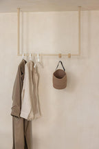 Kleiderstange RUBI mit Kleidungsstücken und einer Tasche an der Wand, minimalistisches Design für Ankleidebereiche.