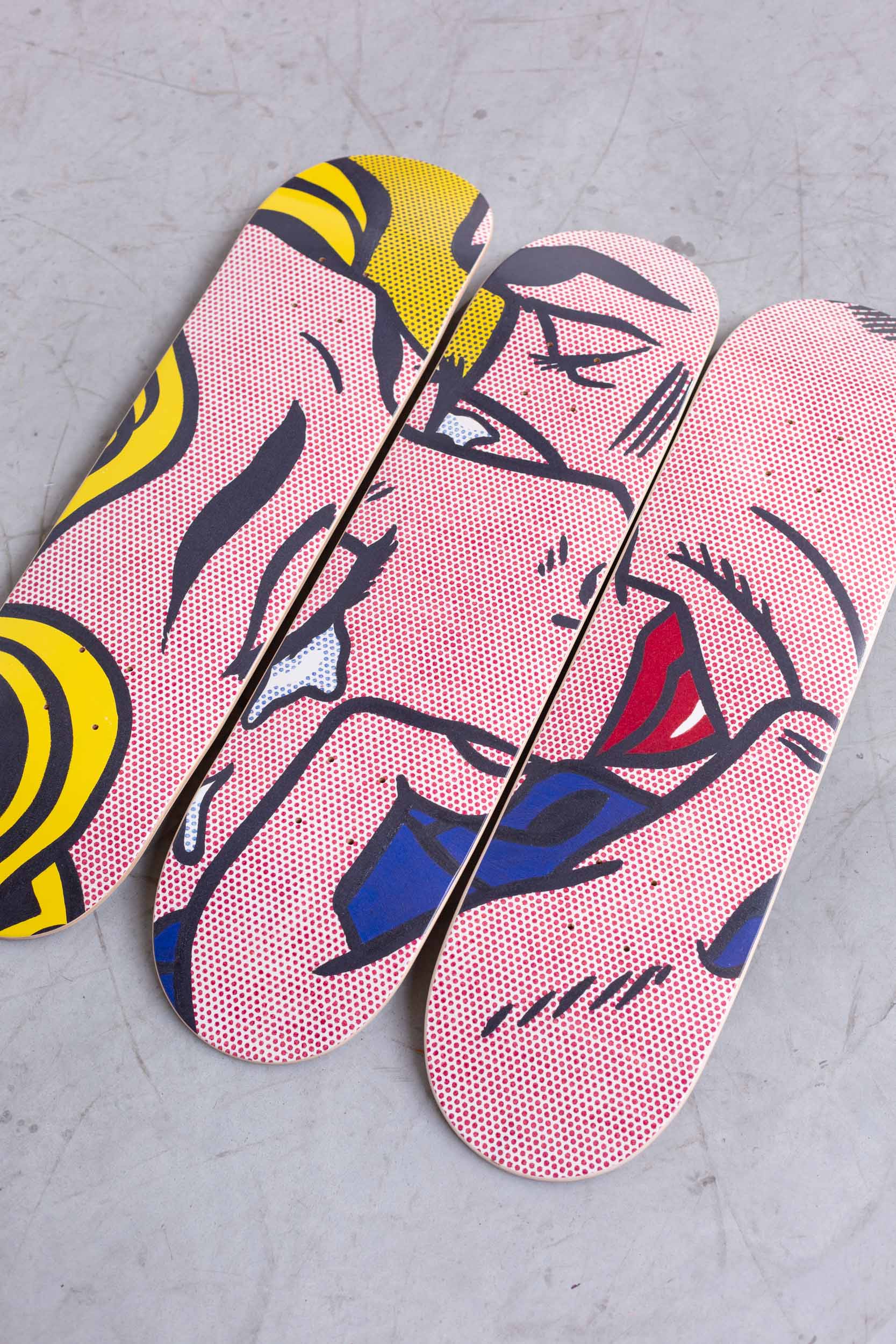 Skateboard Art print from Roy Lichstentein famous Kiss V painting laying on a concrete floor