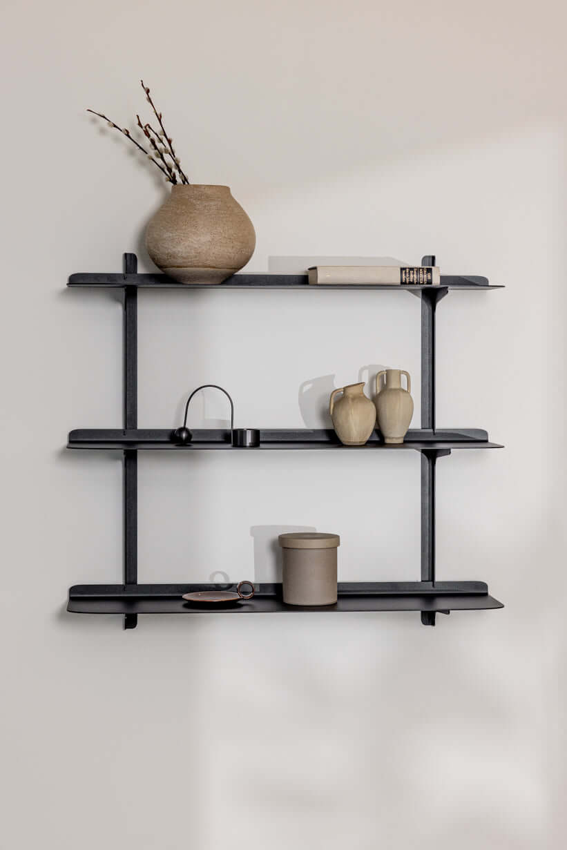 Wandregal LINARA aus Metall mit minimalistischem Design und vier Ablagen, dekoriert mit Vasen und Büchern.