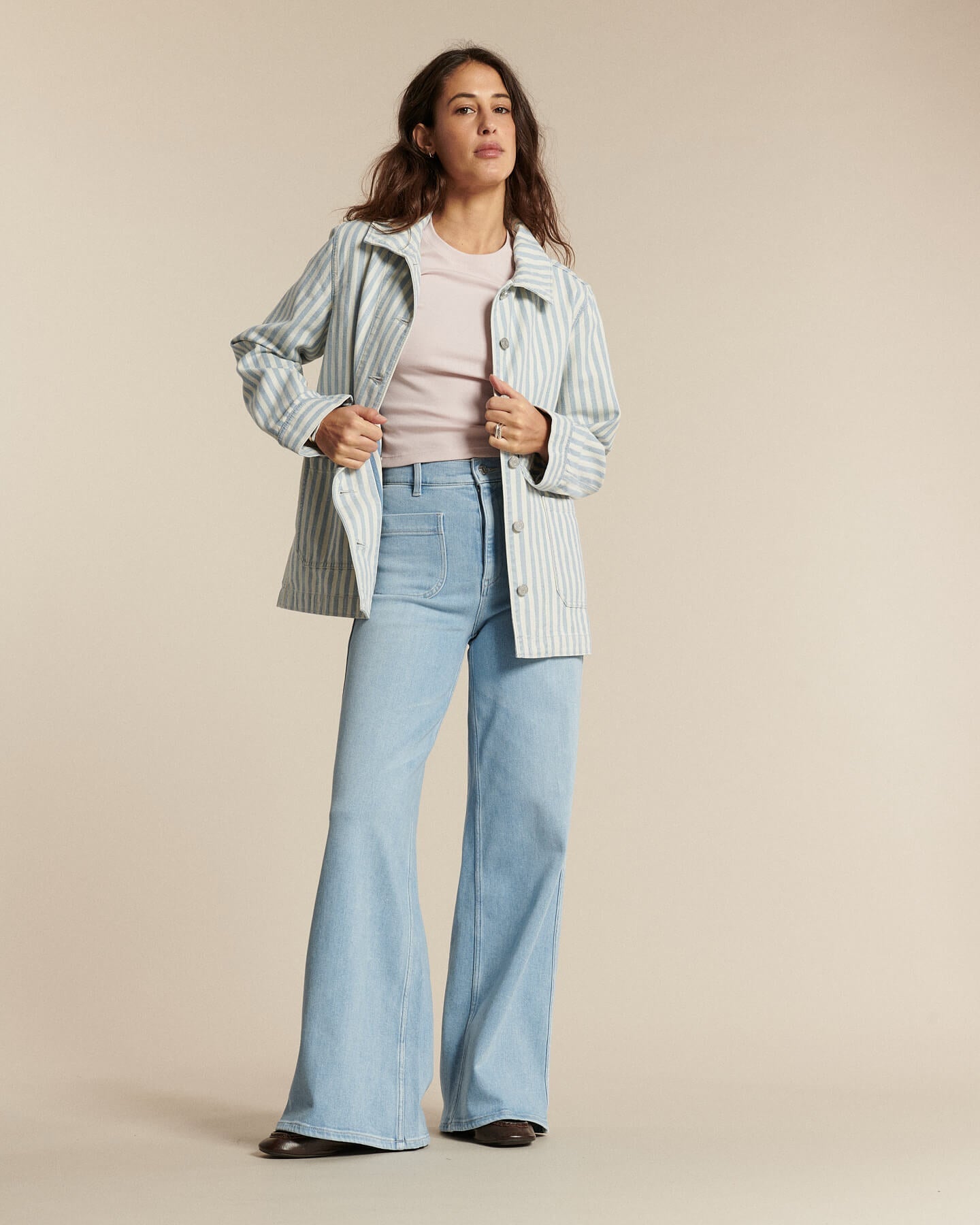 Jean en denim bleu clair avec une coupe flare, taille haute et ajustée aux hanches, idéal pour femme, offrant confort et style décontracté.