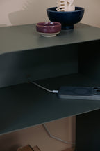 Stehender Nachttisch mit minimalistischem Design, Ladeschale und dekorativen Schalen auf der Ablage.