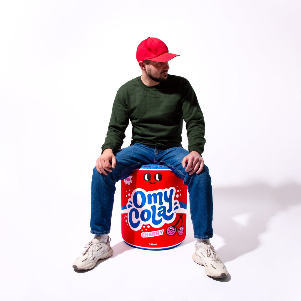 Personne assise sur le coussin géant gonflable OMY Cola – Accessoire pop et fun pour la déco