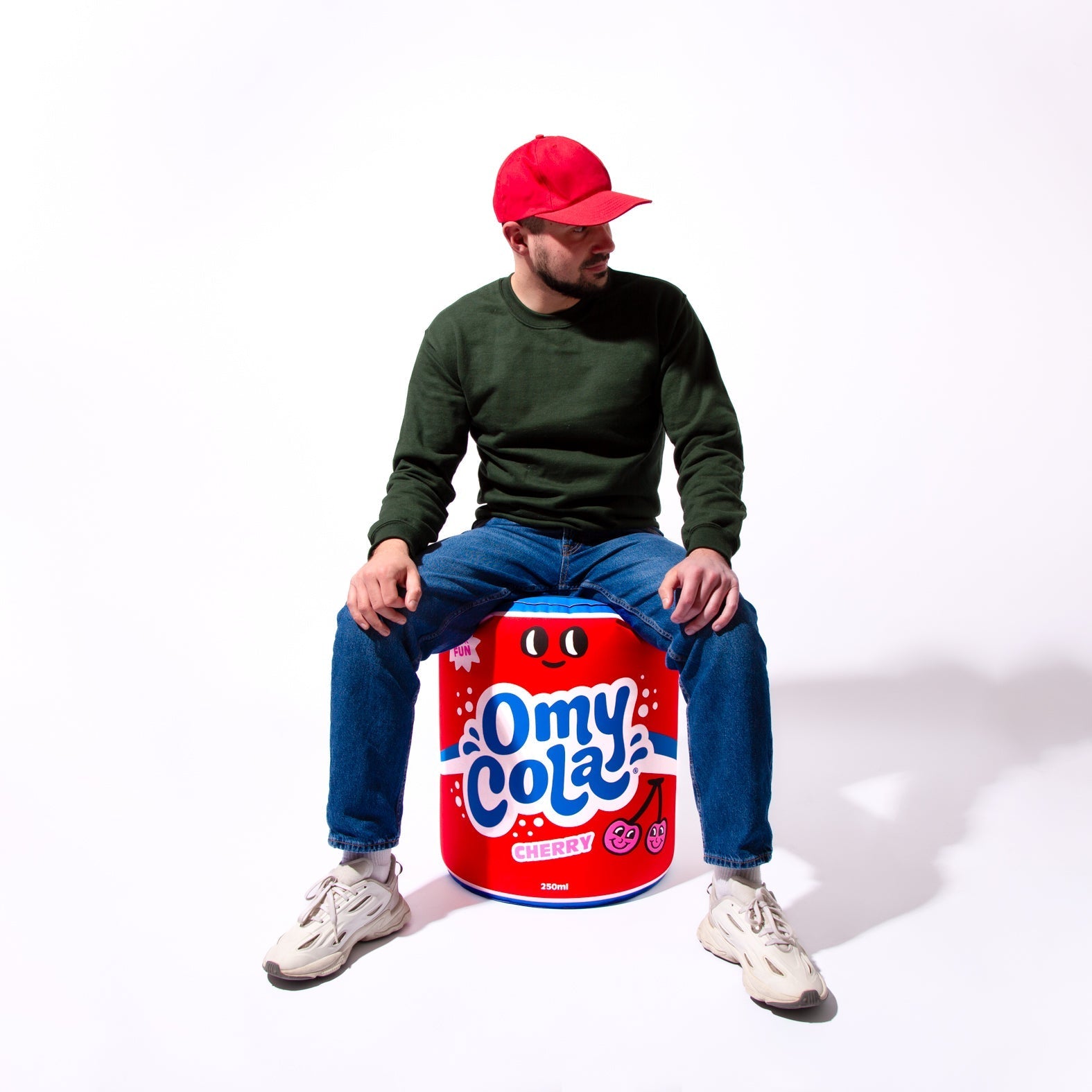 Personne assise sur le coussin géant gonflable OMY Cola – Accessoire pop et fun pour la déco