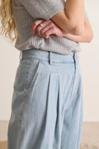 Pantalon bleu en chambray, silhouette fluide avec plis devant, jambes larges et modernes