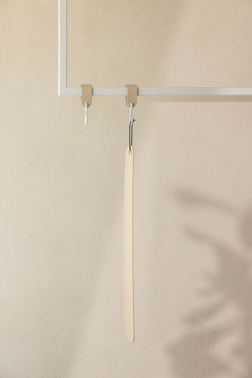 Schuhlöffel TILO aus hochwertigem Metall an einem minimalistischen Haken in modernem Interieur.