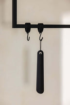 Schuhlöffel TILO in Schwarz an Haken, minimalistisches Design aus hochwertigem Metall.