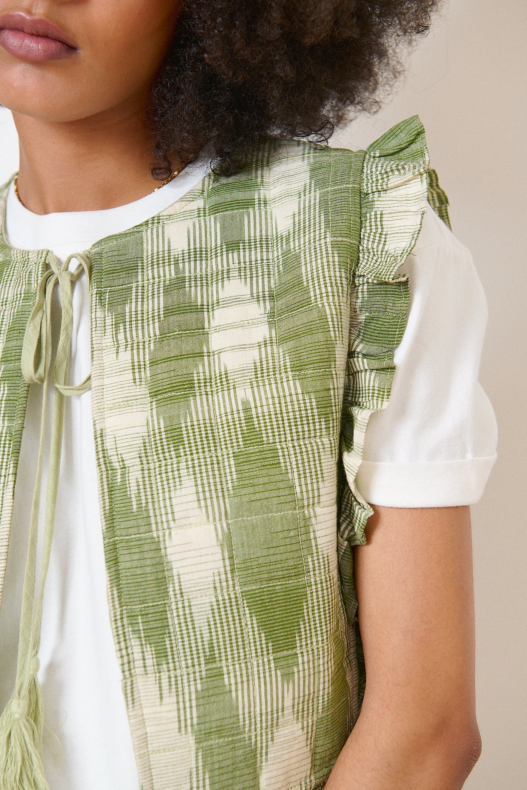 Veste kaki bohème sans manches en tissu ikat, volants élégants et col avec lien à pompons