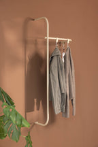 Moderne Garderobe TAMINA mit minimalistischen Metallstangen und Kleidung in einem stilvollen Raum.