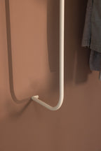 Detailaufnahme der Garderobe TAMINA mit weißem Metallhaken an einer braunen Wand.