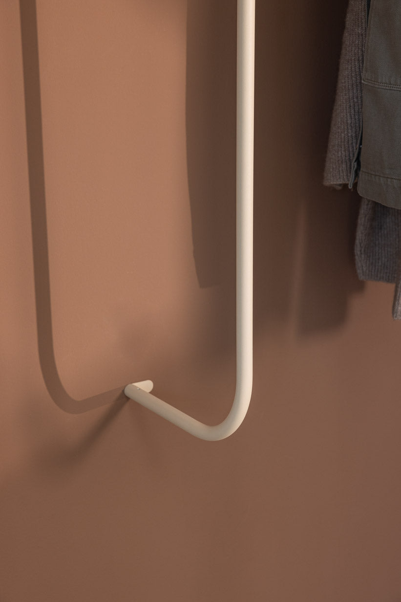 Detailaufnahme der Garderobe TAMINA mit weißem Metallhaken an einer braunen Wand.